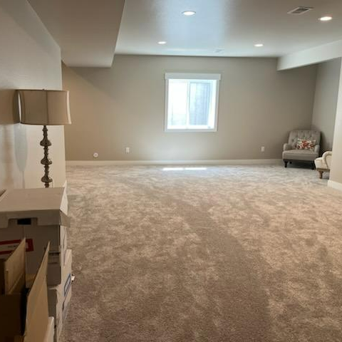 A living room with carpet and a window, suitable for a long distance moving company in Casper, Wyoming.