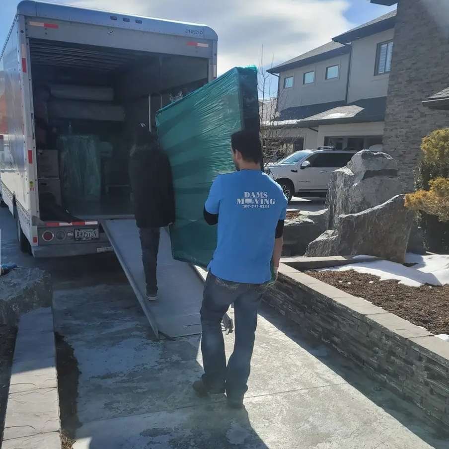 A man in a blue shirt loading a moving truck for a long distance move with the help of moving helpers from a company in Casper Wyoming.