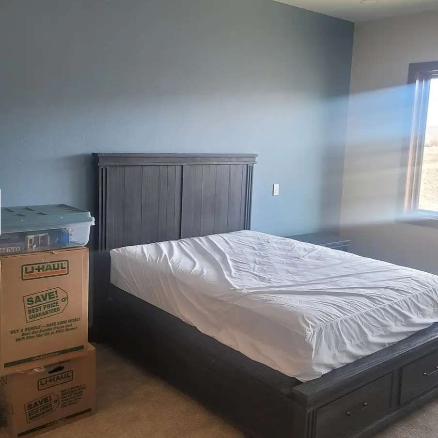 A bedroom with a bed and a box next to it, suitable for the services of Dams Moving Company in Casper Wyoming.