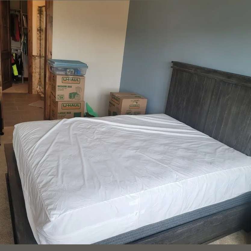 A long distance moving company in Casper Wyoming providing moving helpers for transporting a bed with a mattress and box spring to a room.