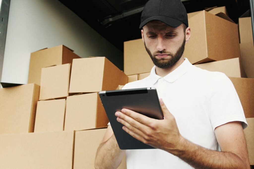 A man with a tablet in front of moving boxes.