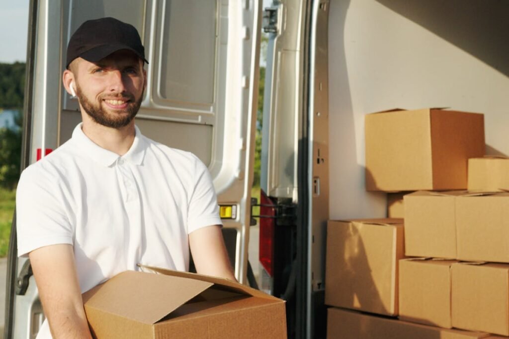 A man holding boxes in front of a moving truck, illustrating stress-free moving.